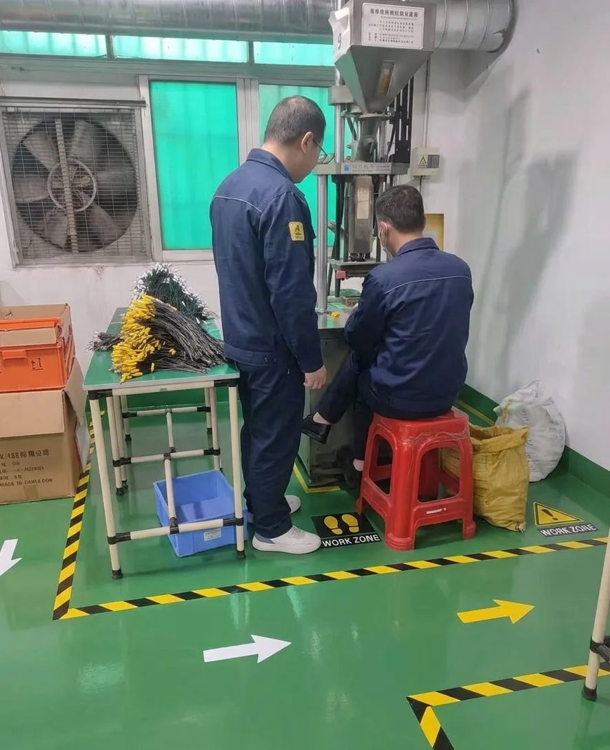 Two technicians quality testing and custom manufacturing wire harnesses on an injection molding machine at Longyd facility to ensure RoHS and CE compliance.